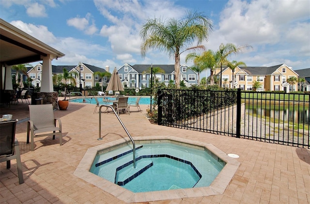 pool featuring a patio, fence, a residential view, and a hot tub