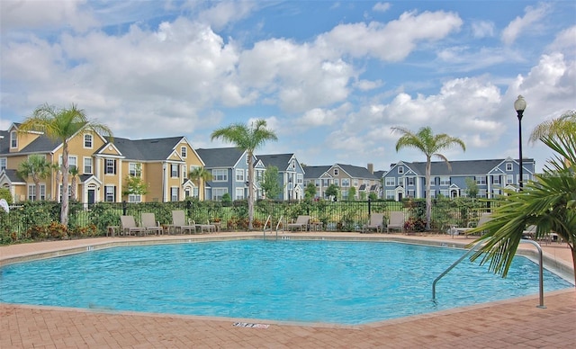 community pool featuring fence and a residential view