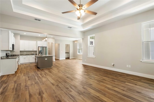 kitchen with visible vents, baseboards, open floor plan, a tray ceiling, and stainless steel appliances