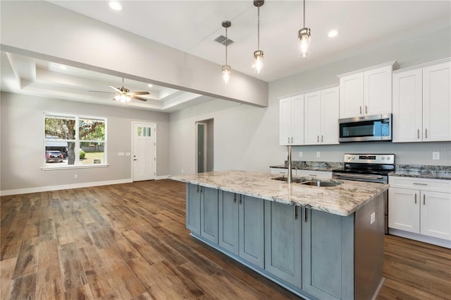 kitchen with open floor plan, stainless steel appliances, white cabinetry, a raised ceiling, and a sink