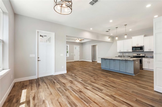 kitchen featuring visible vents, open floor plan, wood finished floors, white cabinetry, and appliances with stainless steel finishes