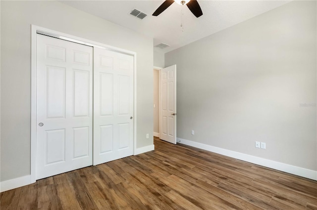 unfurnished bedroom featuring wood finished floors, visible vents, a closet, and baseboards