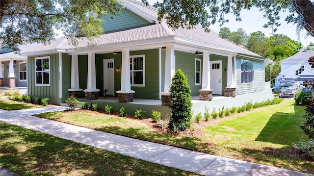 view of front of property featuring a porch, a shingled roof, and a front yard