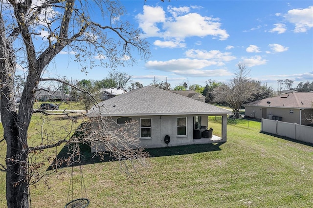 view of side of property with a shingled roof, fence, stucco siding, a yard, and a patio