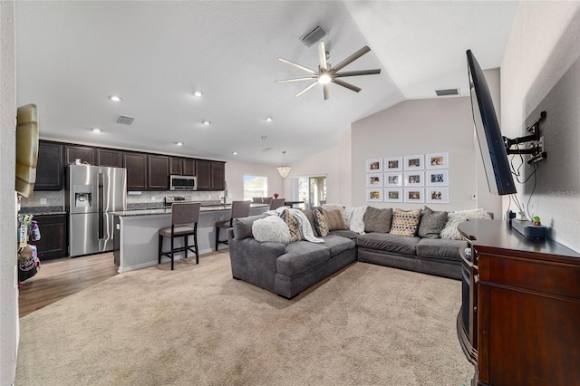 living area featuring visible vents, lofted ceiling, and ceiling fan