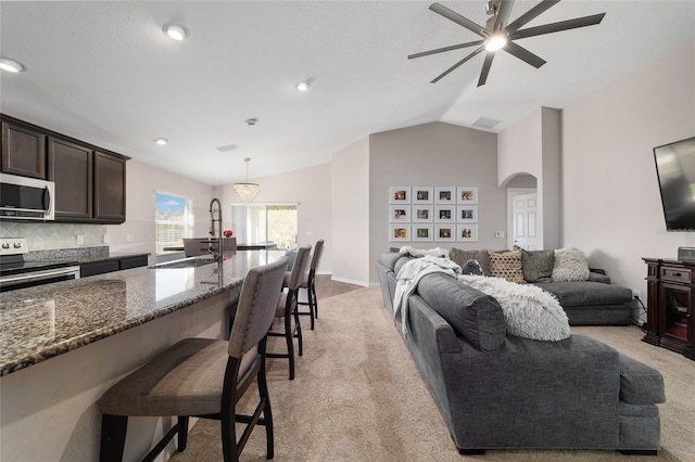 living room featuring baseboards, arched walkways, ceiling fan, vaulted ceiling, and light carpet