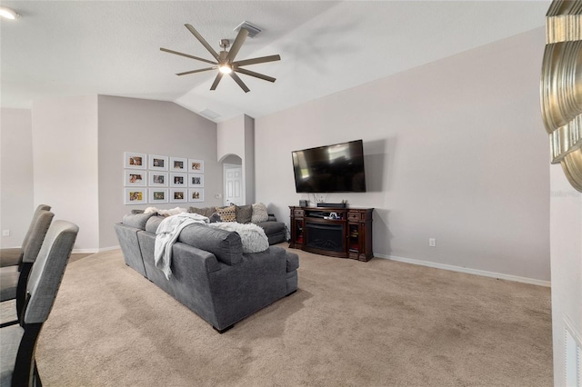 carpeted living area with arched walkways, baseboards, ceiling fan, and vaulted ceiling