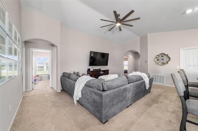 living room featuring vaulted ceiling, arched walkways, visible vents, and light carpet