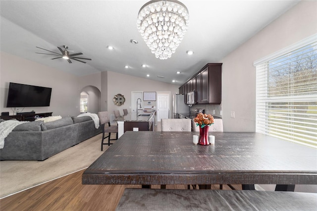 dining room with wood finished floors, recessed lighting, arched walkways, vaulted ceiling, and ceiling fan with notable chandelier