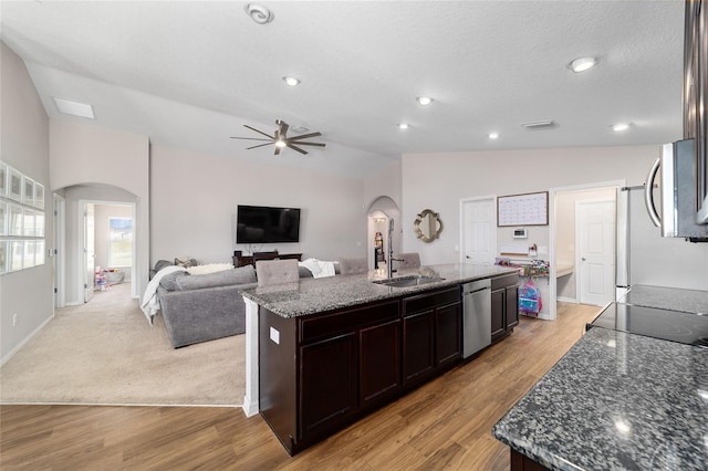 kitchen with lofted ceiling, arched walkways, appliances with stainless steel finishes, and a sink