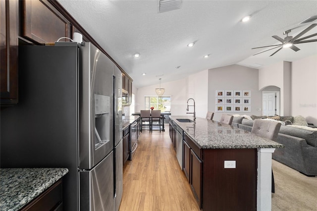 kitchen featuring visible vents, stainless steel fridge with ice dispenser, open floor plan, a breakfast bar, and a sink