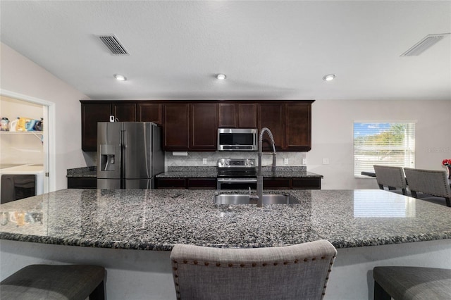 kitchen with a sink, stainless steel appliances, a kitchen bar, and visible vents