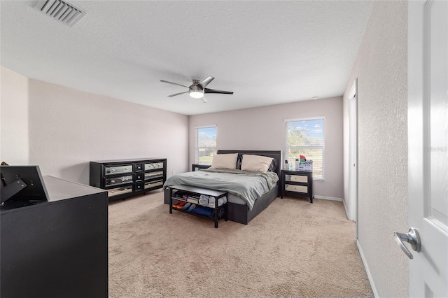 carpeted bedroom with visible vents, a ceiling fan, a textured ceiling, baseboards, and a textured wall