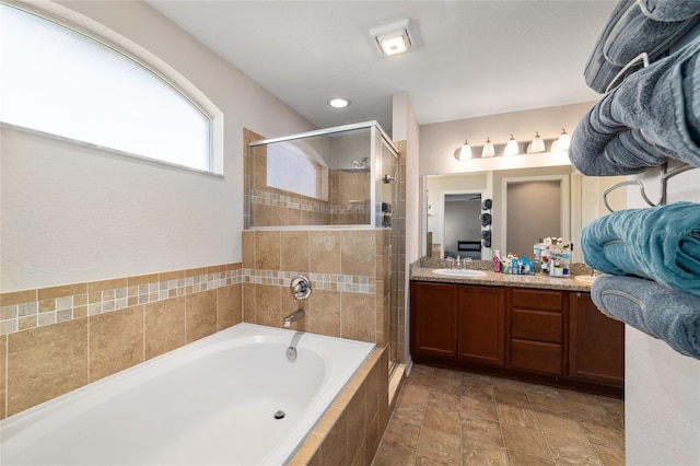 bathroom featuring a stall shower, vanity, and a garden tub