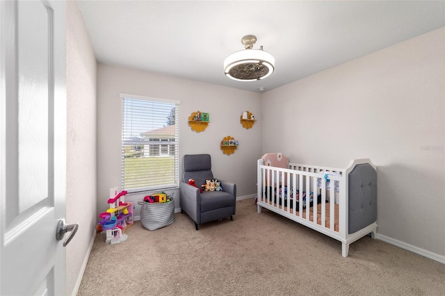 bedroom featuring baseboards, a nursery area, and carpet flooring