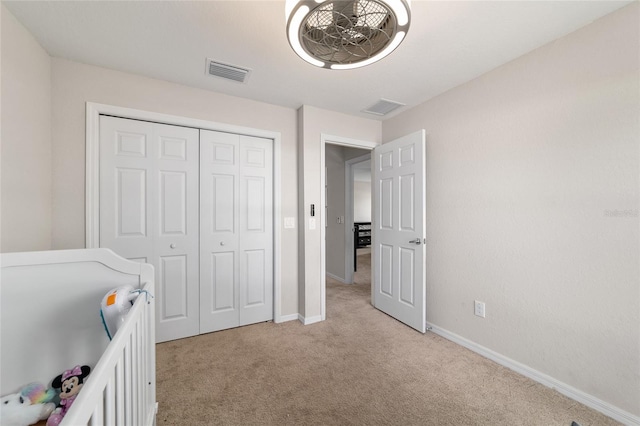 unfurnished bedroom featuring baseboards, visible vents, a closet, and light carpet