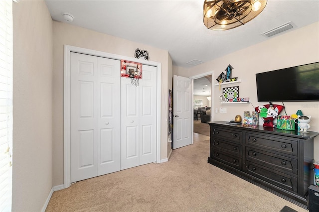 bedroom with baseboards, visible vents, a closet, and light carpet