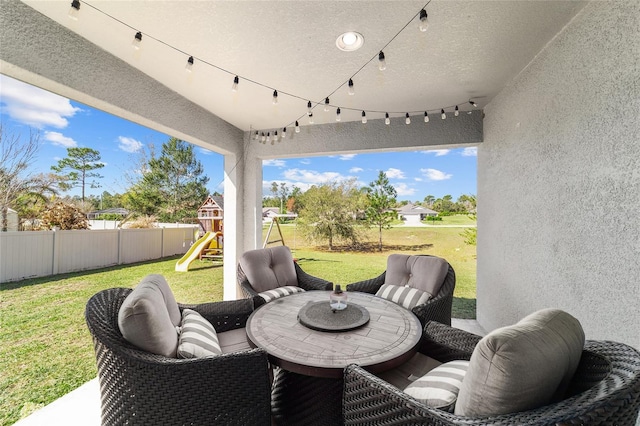 view of patio / terrace with outdoor dining space, a playground, and a fenced backyard