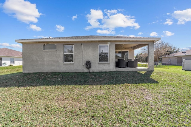 back of house featuring stucco siding, fence, a yard, and a patio area