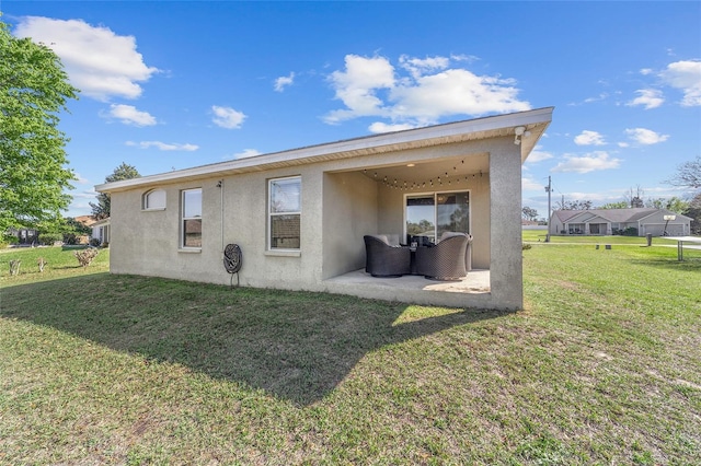 rear view of house featuring a patio, a lawn, and stucco siding