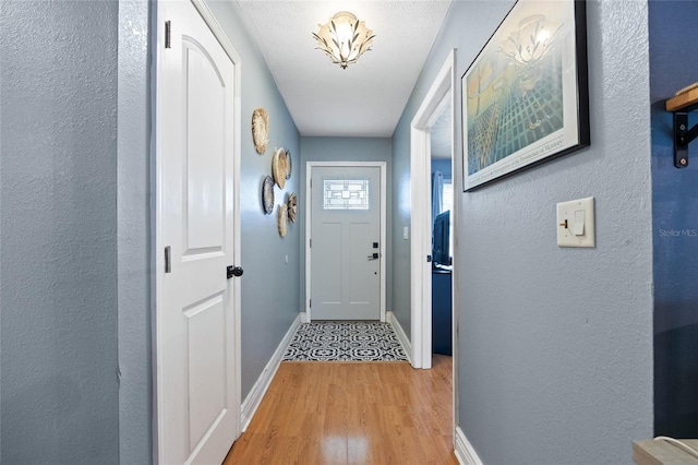 doorway featuring baseboards and light wood finished floors