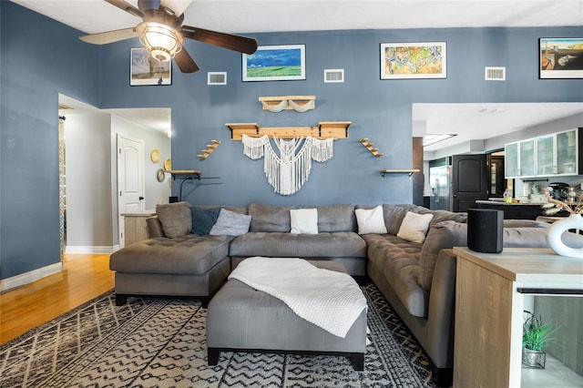 living room with visible vents, baseboards, and wood finished floors