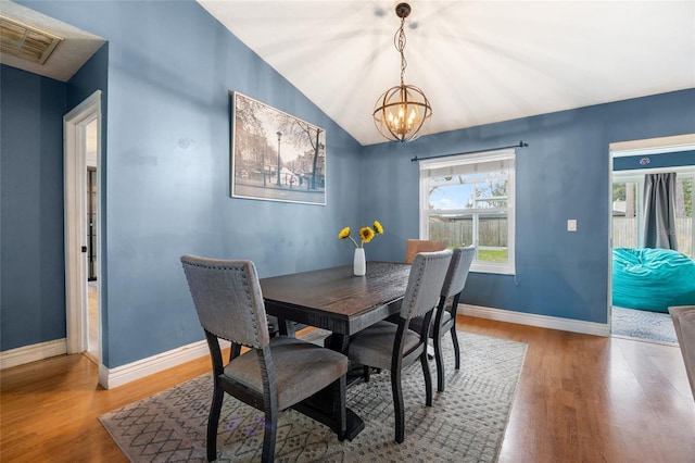 dining space with visible vents, baseboards, wood finished floors, and vaulted ceiling