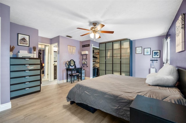 bedroom with a ceiling fan, wood finished floors, visible vents, baseboards, and a textured ceiling