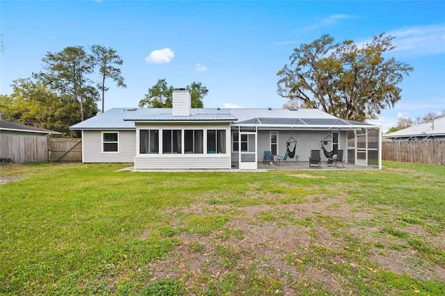 rear view of property with a patio, a fenced backyard, a yard, metal roof, and a chimney