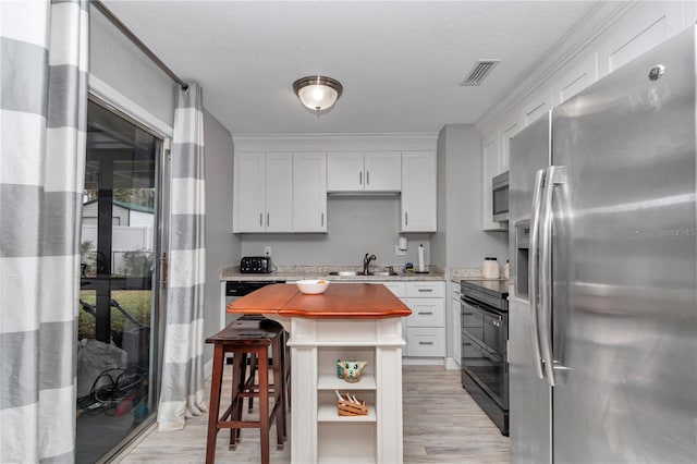 kitchen with visible vents, white cabinetry, stainless steel appliances, and a sink