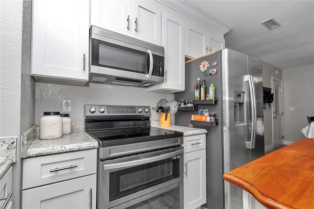 kitchen featuring light stone countertops, visible vents, white cabinets, appliances with stainless steel finishes, and a textured ceiling