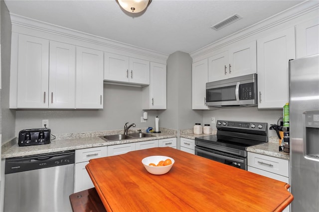 kitchen featuring visible vents, a sink, butcher block countertops, stainless steel appliances, and white cabinetry