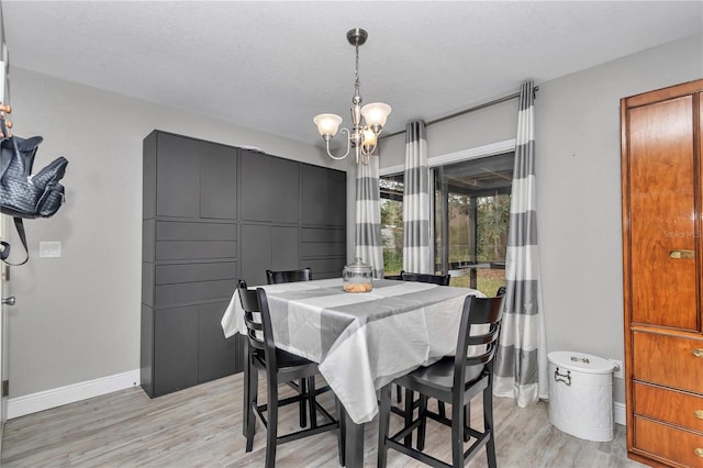 dining area with an inviting chandelier, light wood-style floors, baseboards, and a textured ceiling