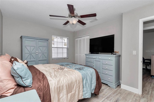 bedroom featuring light wood-type flooring, visible vents, a closet, baseboards, and ceiling fan