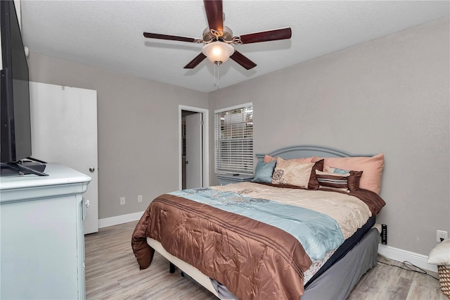 bedroom featuring light wood-style flooring, a textured ceiling, baseboards, and ceiling fan