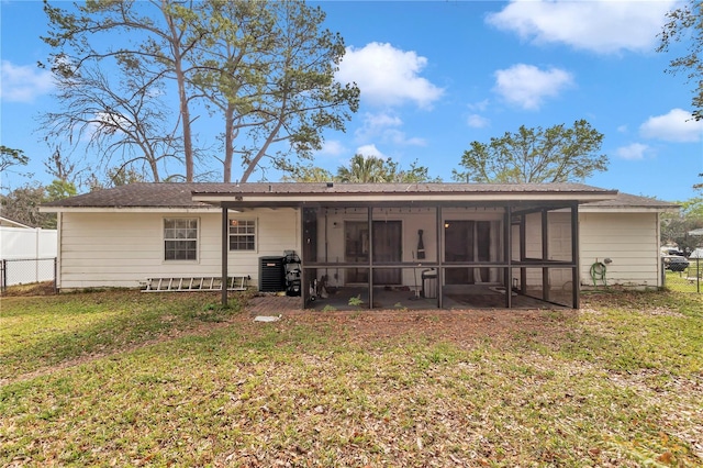 back of property with central AC unit, a yard, fence, and a sunroom