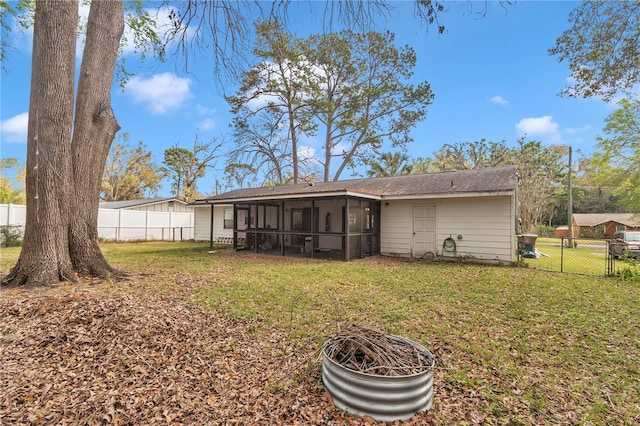 back of property with a gate, a lawn, a fenced backyard, and a sunroom