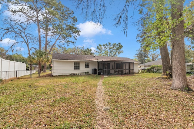 rear view of property with a lawn, central AC, a fenced backyard, and a sunroom