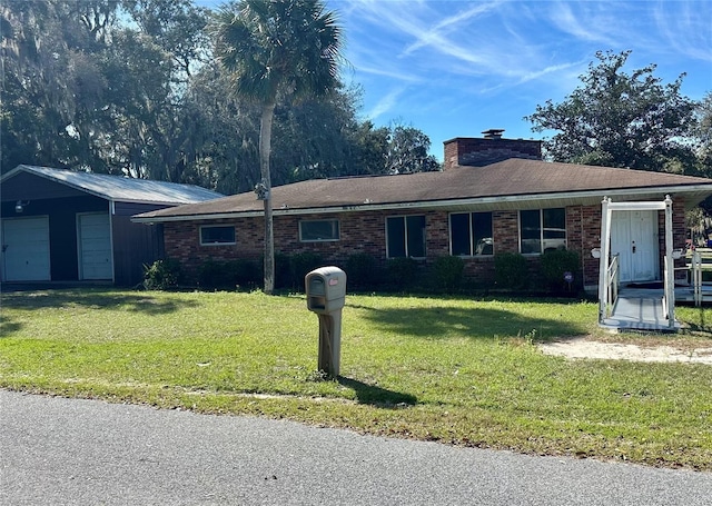 single story home featuring an outdoor structure, a front yard, a garage, brick siding, and a chimney