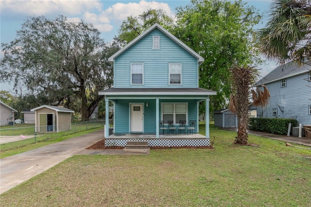 view of front of house with fence, a porch, a front lawn, an outdoor structure, and a storage shed