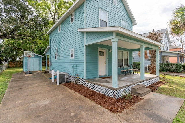 view of front of property with an outdoor structure, a storage unit, central AC unit, and covered porch