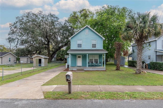 view of front facade with fence, covered porch, a front lawn, concrete driveway, and an outdoor structure