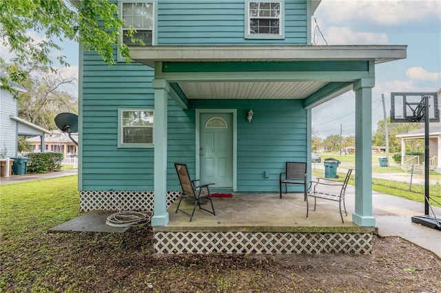 property entrance with a lawn and covered porch