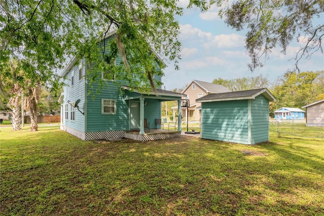 back of property featuring an outdoor structure, fence, a lawn, and a shed