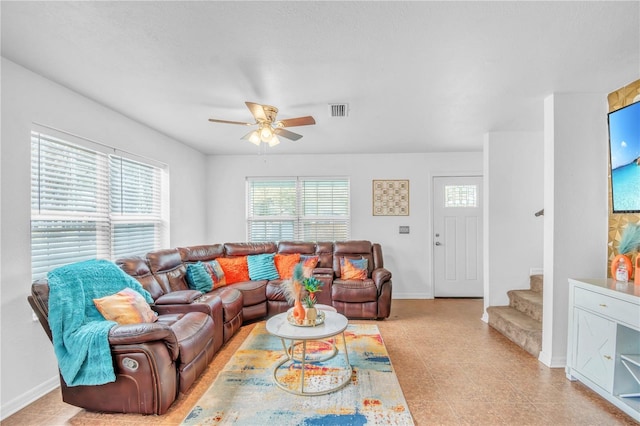 living area with stairway, a ceiling fan, visible vents, and baseboards