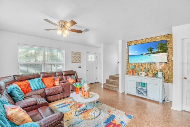 living room featuring stairs, a ceiling fan, and visible vents