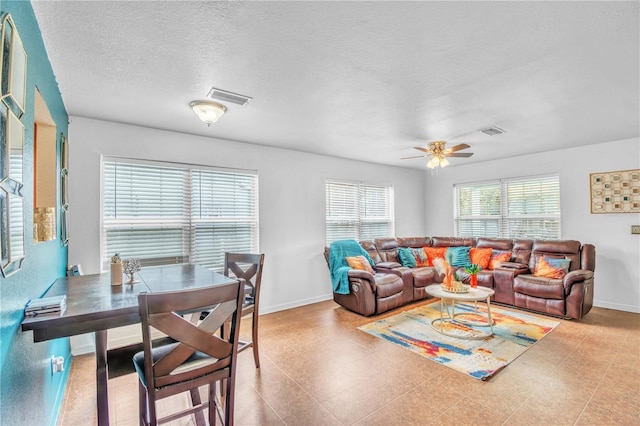 living area with visible vents, a textured ceiling, and baseboards