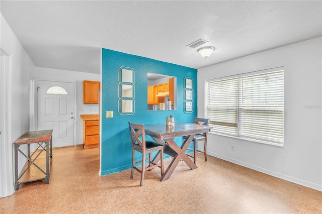 dining space with visible vents, a textured ceiling, and baseboards