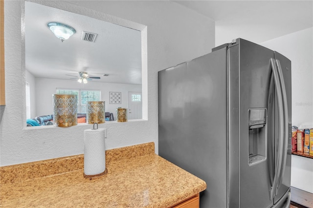 kitchen featuring visible vents, ceiling fan, light countertops, stainless steel refrigerator with ice dispenser, and a textured wall