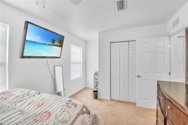 bedroom with baseboards, visible vents, light carpet, and a closet